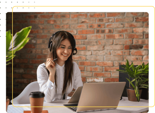 A woman with headphones sitting at a coffee sho, looking at a laptop