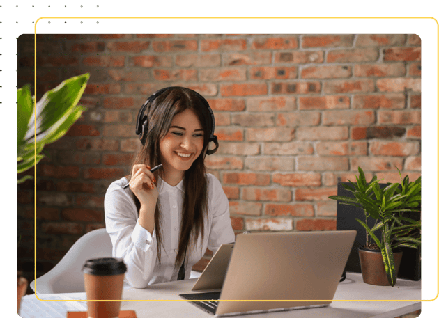 A woman with headphones sitting at a coffee sho, looking at a laptop