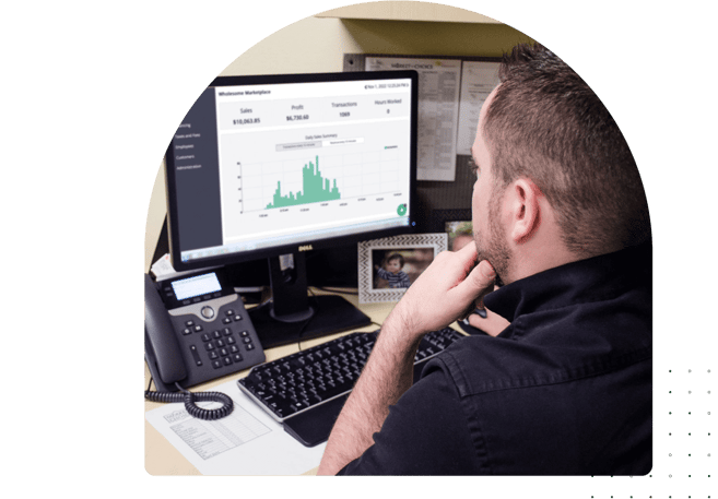 A man sitting in a cubicle looking at a compuiter screen with a chart